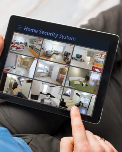 Man,Looking,At,Home,Security,Cameras,On,Tablet,Computer