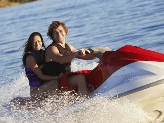 Happy young Caucasian couple riding jet ski on lake